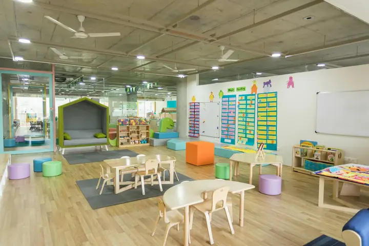 Childcare room with small tables, chairs and learning displays